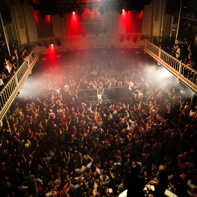 Sold Out Show Paradiso Wide view of a sold-out Paradiso Amsterdam with a crowded dance floor. DJ Lamírla stands at the center behind the decks, surrounded by an energetic audience.